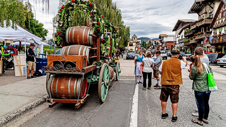 large barrels of beer loaded on a carriage, men and women in both traditional Bavarian attire and regular clothing