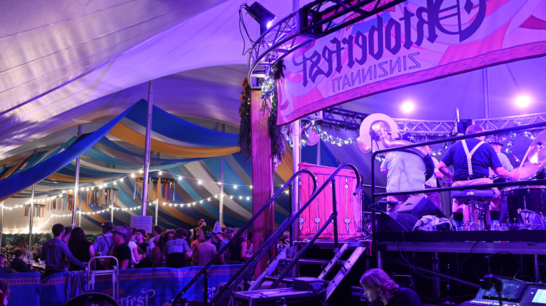 Colorful Oktoberfest tent, full of people, purple-pink lighting
