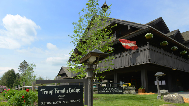 distinctly Bavarian architecture house, austrian flag flutters in the balcony, board reads "Trapp Family Lodge"