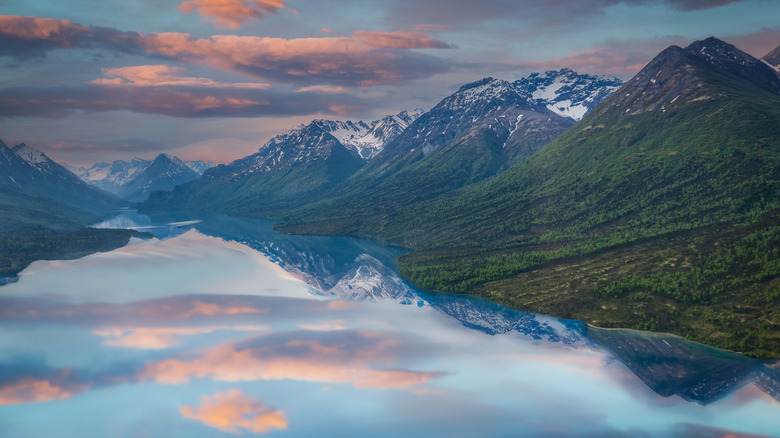 Mountains and sunrise or sunset reflect on Lake Clark in Alaska