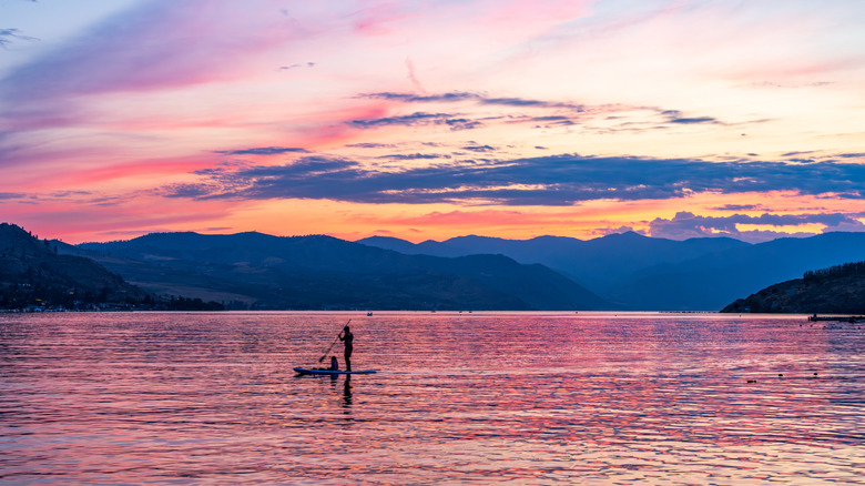 A dramatic sunset over Lake Chelan, with the silhouette of a couple paddleboarding.