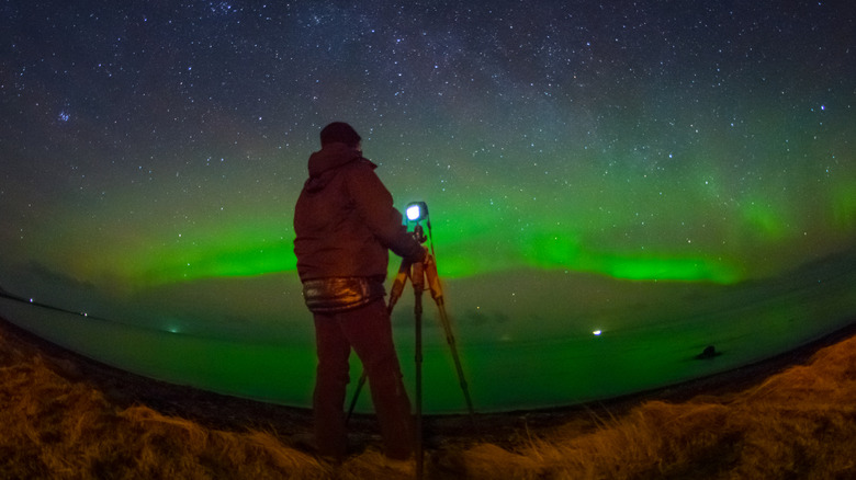 A photographer's silhouette against the northern lights