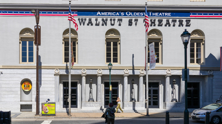 The Walnut Street Theatre, a gray building with arched windows and columns, and a blue banner with a red stripe and white stars reading "America's Oldest Theatre"