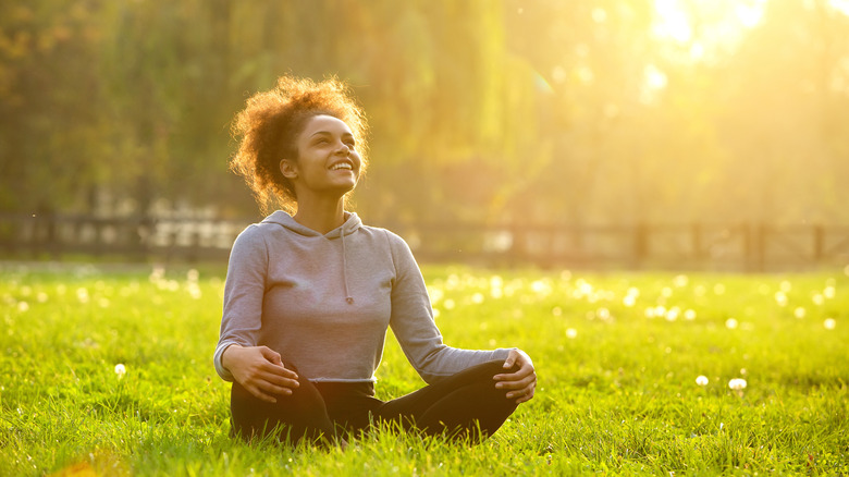 a woman sitting in the sun looking up to the sky