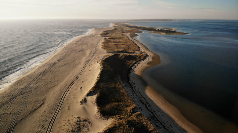 A long strip of and and scrubland with water on either side