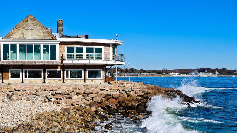 Rocky jetty with building and waves crashing blue skies Narragansett Rhode Island