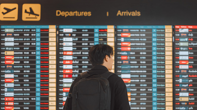 Man checking the flight info board at the airport