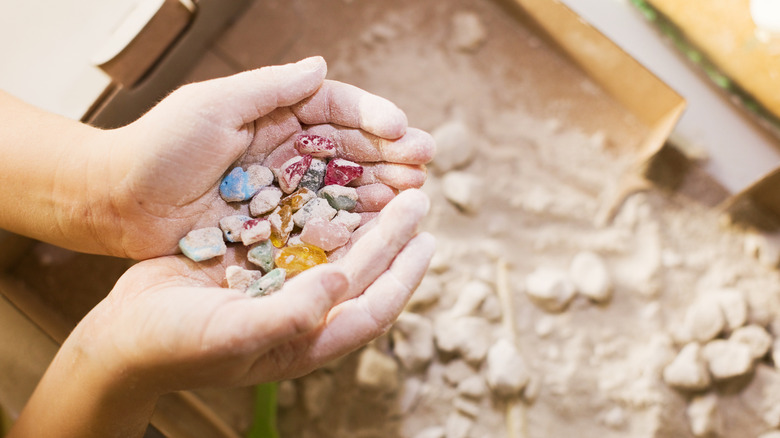 A child holding various stones extracted from the sandbox