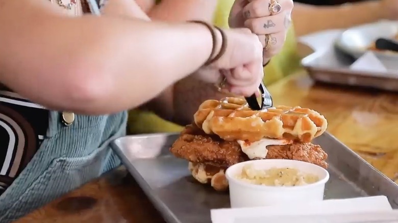 cutting into chicken and waffles