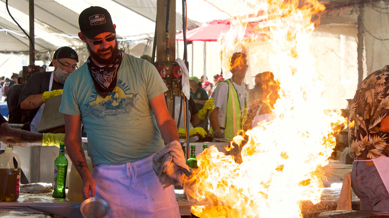A chef cooking in a flaming pan at the Gilroy Garlic Festival