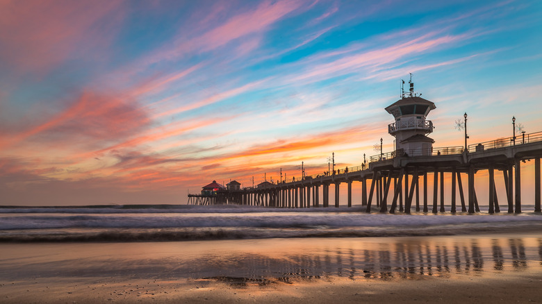 Huntington Pier jutting into the Pacific Ocean with sunset sky colors on the horizon.