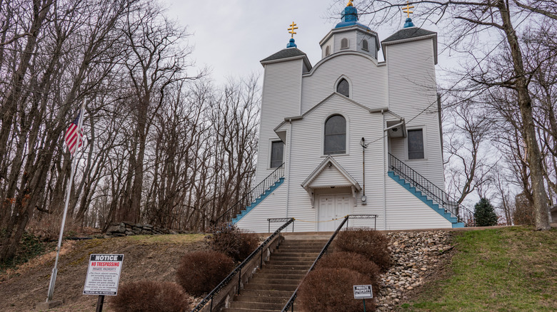 a white church at the top of steep steps with a no trespassing sign in front