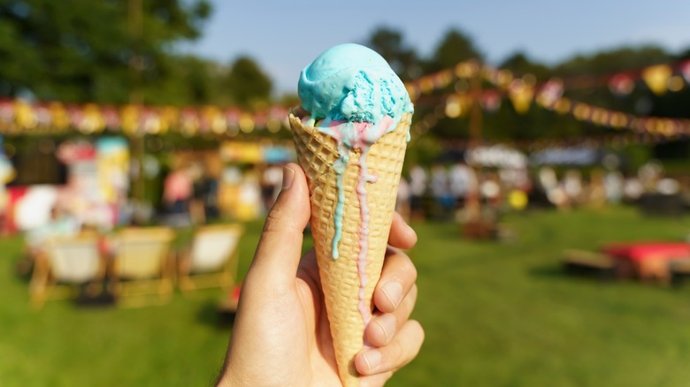 Hand holding a melting waffle ice cream cone outside
