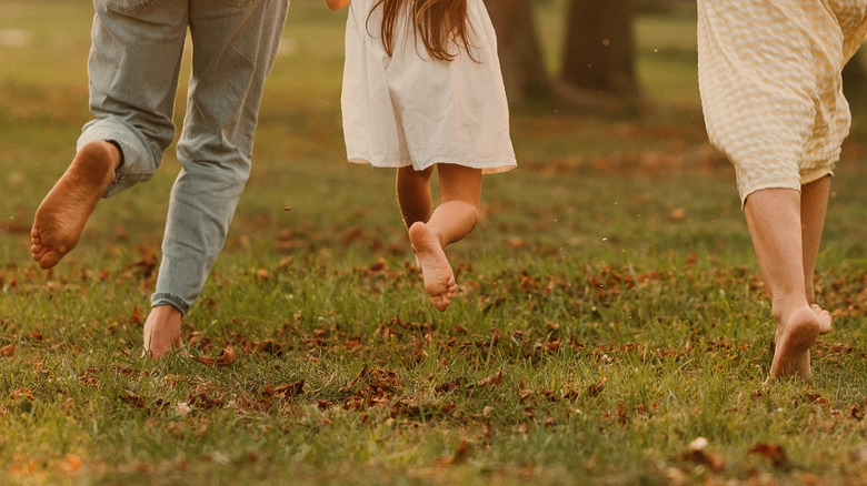 Three sets of bare feet walking through a park