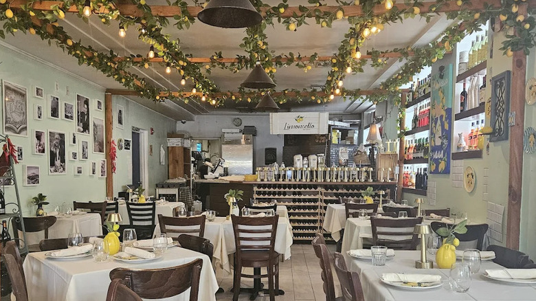 Daytime interior view of Limoncello Italian restaurant in Miami, Florida with lemon garlands draped on the ceiling, black and white photos on the walls, and lemon decor on white tablecloths