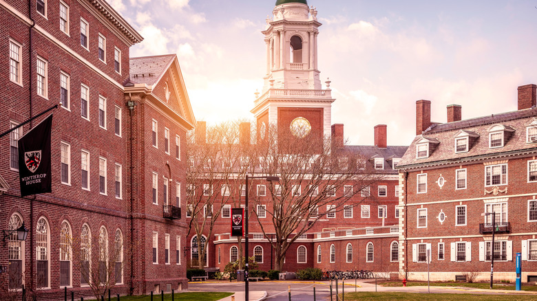 The brick walls and single tower of Harvard Hall are set against a fading sun
