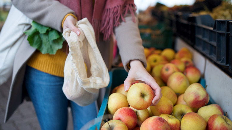a woman picking out apples at a farmers market