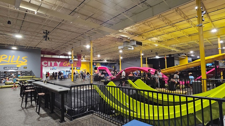 Kids play on huge pink and yellow slides at an indoor adventure park in Virginia.