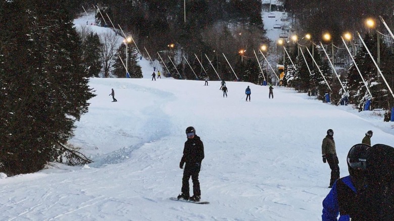 People skiing and snowboarding on a snowy slope at Blue Mountain Resort in the Poconos