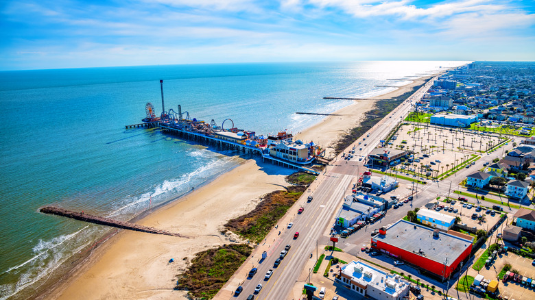 Sandy beach and pier with amusement park rides at Galveston Seawall