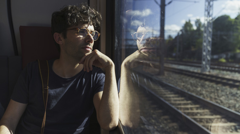 male train passenger looking out train window