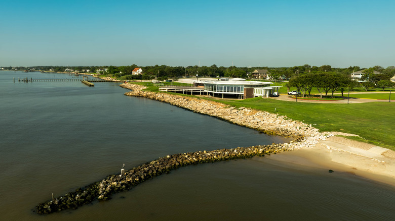 A grassy park with a sandy shore, a fishing pier, and a pavilion at Sylvan Beach, near Pasadena, Texas.