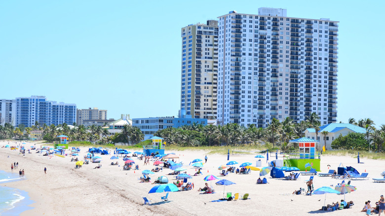 People sunbathing and walking on Pompano Beach, Florida.