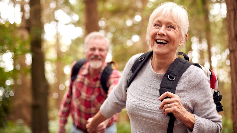 A senior couple runs with abandon through the woods