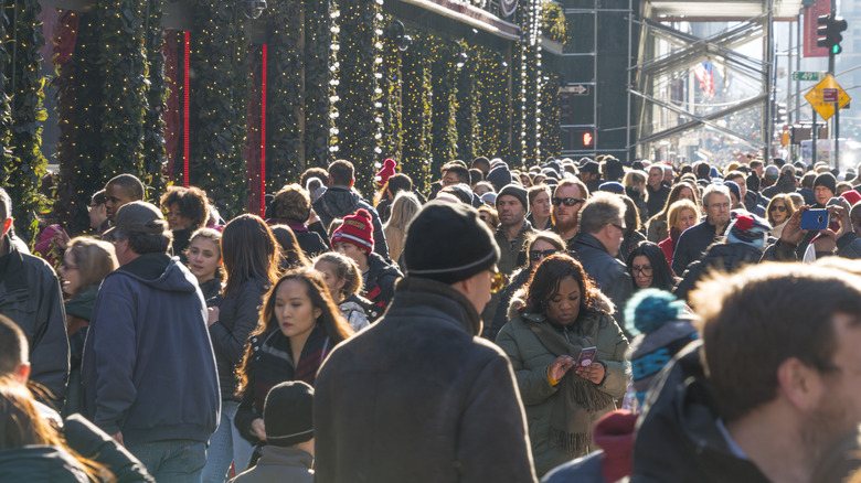 A crowd of people walking down the street in NYC during the holidays