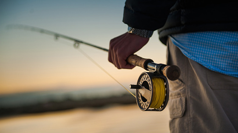 Sunrise over the marsh with man holding a fly rod and reel