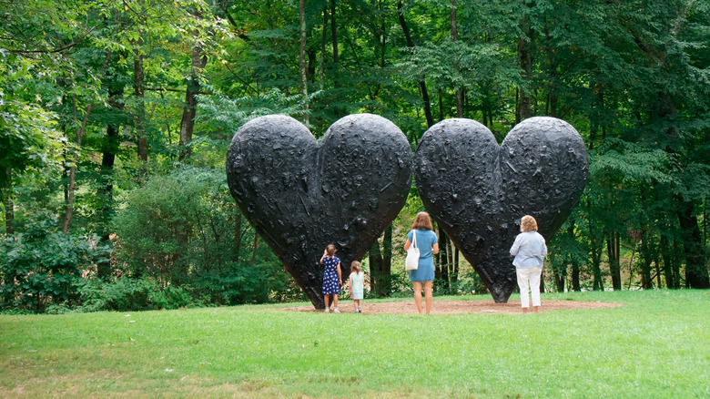 Tourists visiting the sculpture of "Two Big Black Hearts" by Jim Dine in DeCordova sculpture park