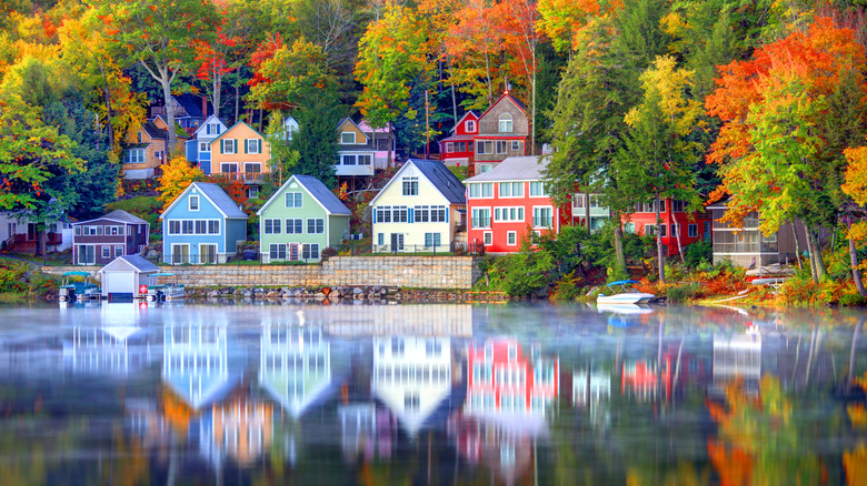 Houses and autumnal forest are reflected in the still waters of Lake Winnipesaukee in New Hampshire