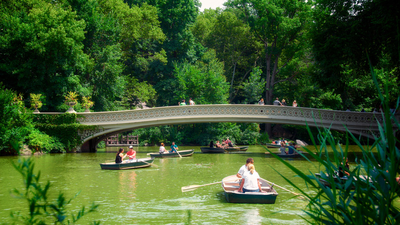 People in rowboats and walking across Bow Bridge in NYC's Central Park