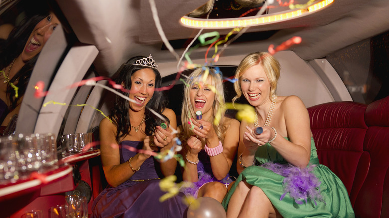 Three women partying in a limousine with confetti