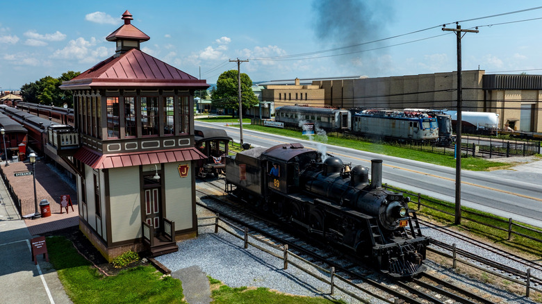A steam locomotive pulls away from the Strasburg Rail Road station