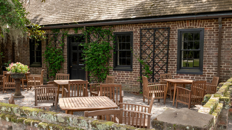 A wooden table and chairs on the patio of the Restaurant at Middleton Place