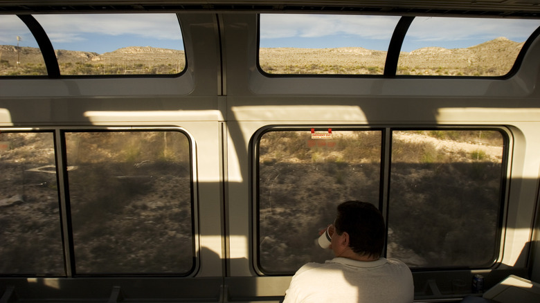 Man sipping coffee with Texas views from the observation car on an Amtrak train