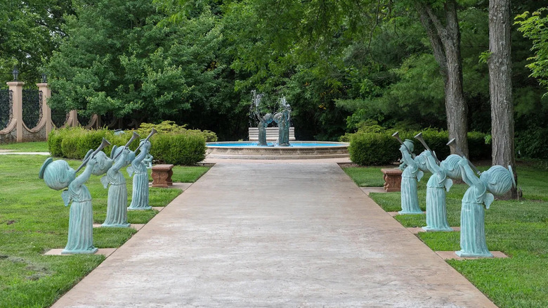 A lush green garden filled with green sculptures of angelic children and flowers