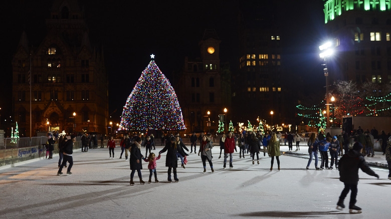People ice skating outside in Syracuse with a Christmas tree in the background