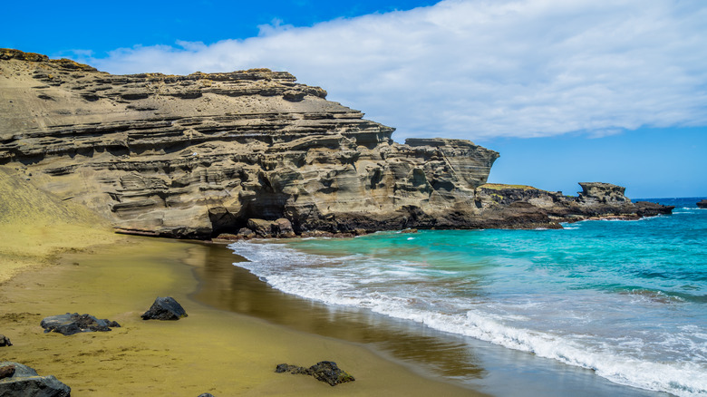 Green sand beach by cliff and ocean