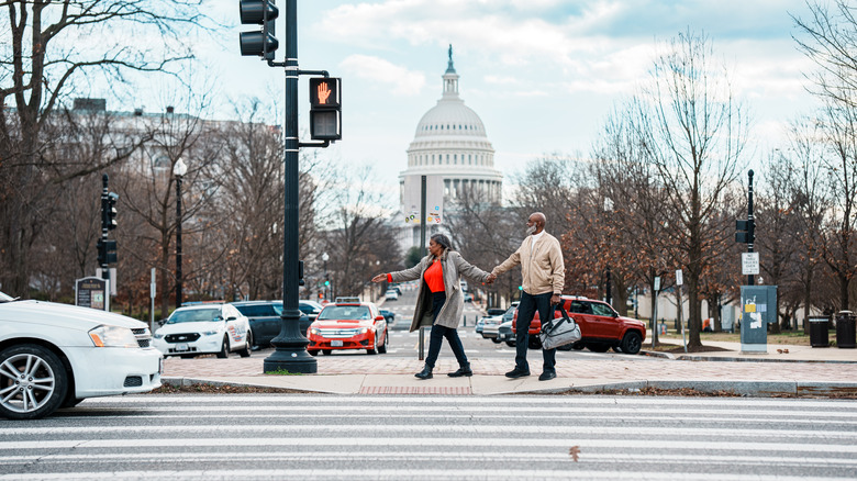 An older couple walking toward a crosswalk in front of the Capitol Building