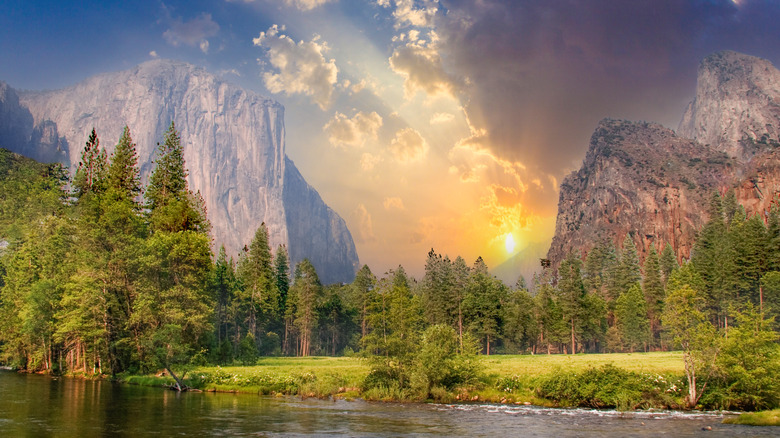 Sun setting behind huge, granite cliffs in Yosemite Valley, at Yosemite National Park.