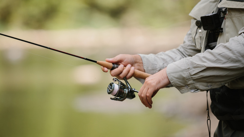 An angler holds a fishing rod in front of a body of water