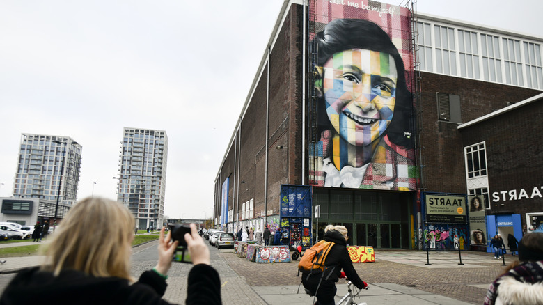 person cycling through NDSM while someone takes a picture of the street art