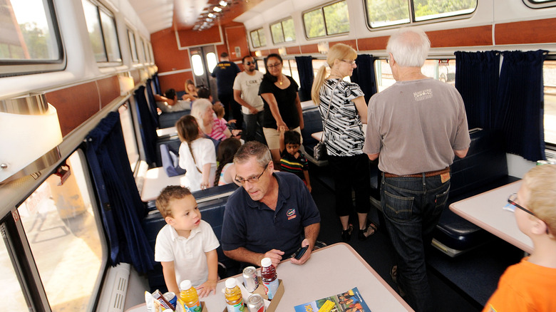 The interior of a train car with passengers walking and sitting