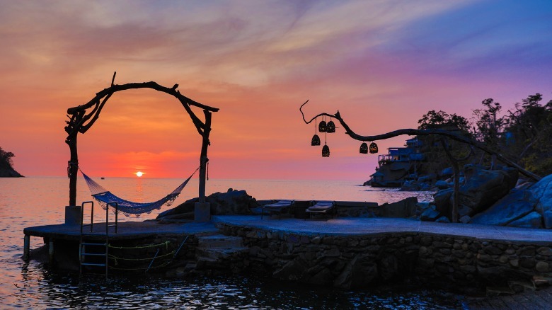 Orange sunset view behind dock and hammock