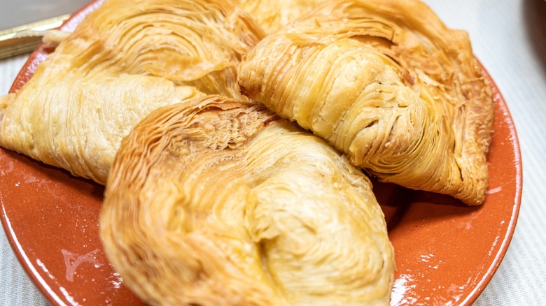 Three Pastel de Chaves pastries on an orange plate