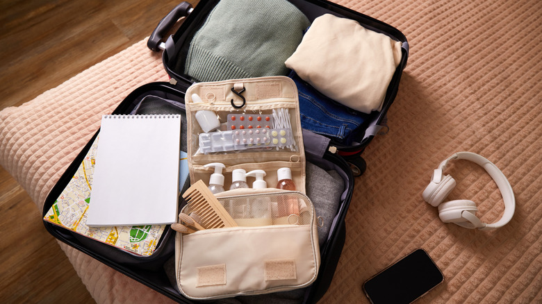 An open suitcase with clothes and an open toiletry bag