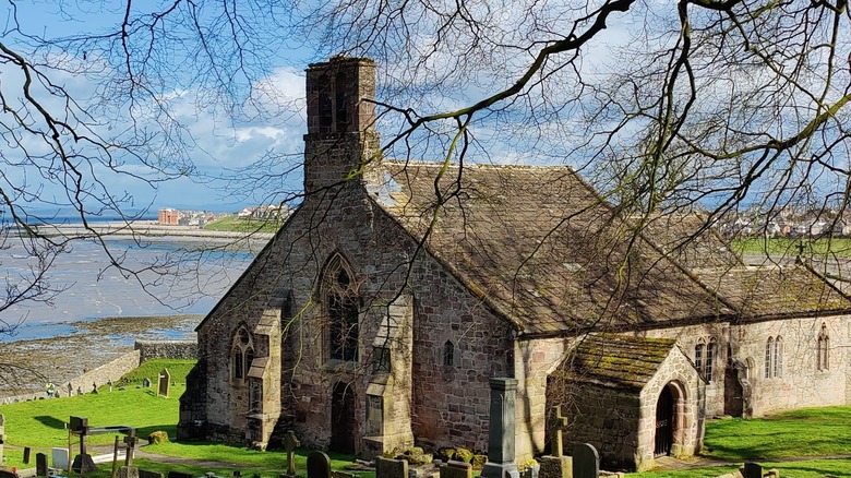 St. Peter's Church, built in the 960s, stands near Heysham, with the sea and Lancashire coastline in the background.