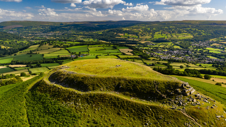 A grassy plateau known as Table Mountain surrounded by fields, with the Welsh town of Crickhowell in the background